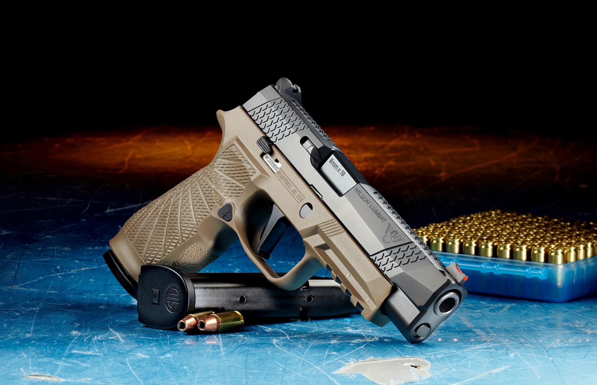 Semi-automatic pistol posed with magazine, two hollow point cartridges, and a container of cartridges in the background